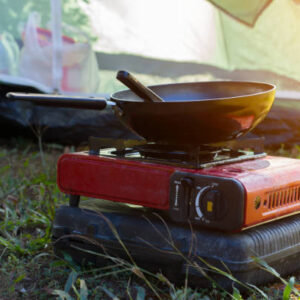 Portable camping stove cooking a meal at an outdoor campsite.